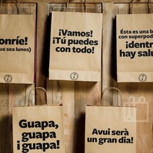 Bolsas de papel kraft con mensajes motivadores colgadas sobre una pared de madera