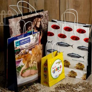 Conjunto de bolsas de papel de diferentes tamaños y diseños apoyadas sobre una superficie de madera