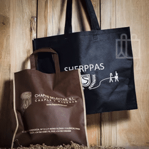 Dos bolsas de compra reutilizables apoyadas sobre una superficie de madera