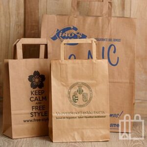 Varias bolsas de papel kraft con logotipos impresos apoyadas sobre una superficie de madera