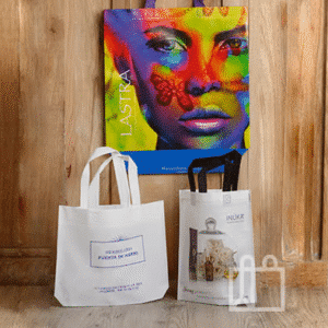 Dos bolsas de papel con diseño artístico colocadas frente a una pared de madera